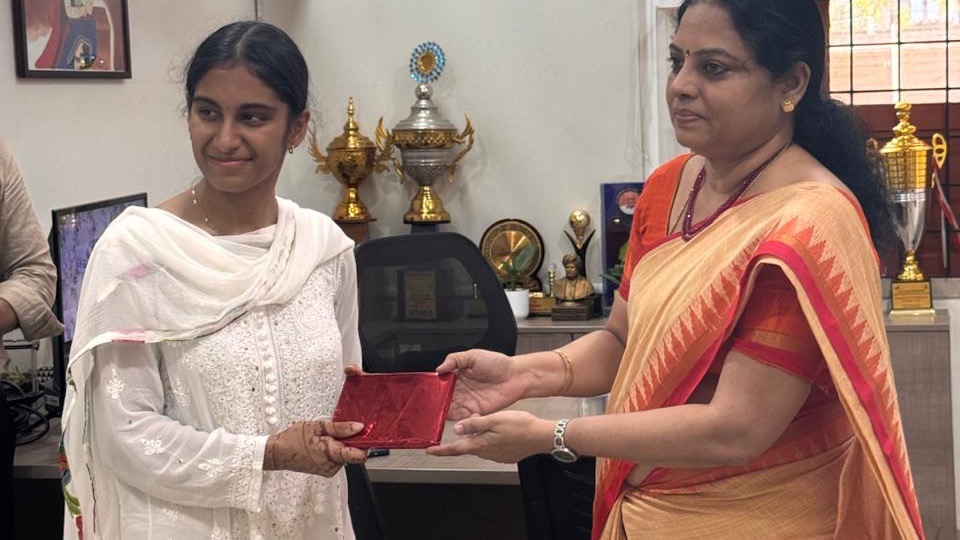 Meha presenting a copy of Learning Through Wonder to a school principal